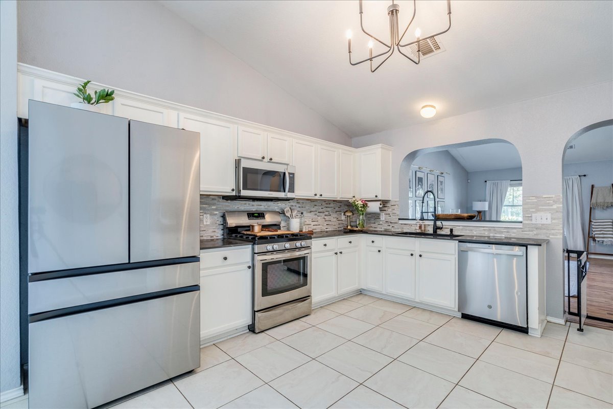 175 Wetzel Kyle, TX 78640 - Photo 2 of 27 A well-appointed kitchen showcasing elegant white cabinetry, sleek appliances, and a vaulted ceiling.