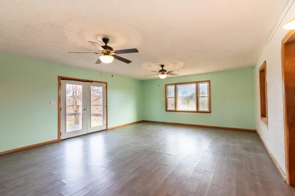 a view of an empty room with window and wooden floor