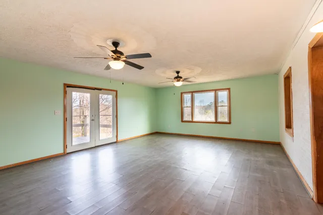 a view of an empty room with window and wooden floor