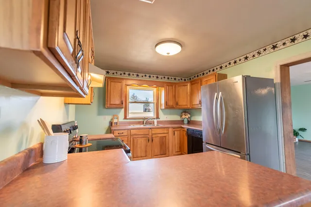 a large kitchen with stainless steel appliances a refrigerator a stove a washer dryer and a dining table with wooden floor