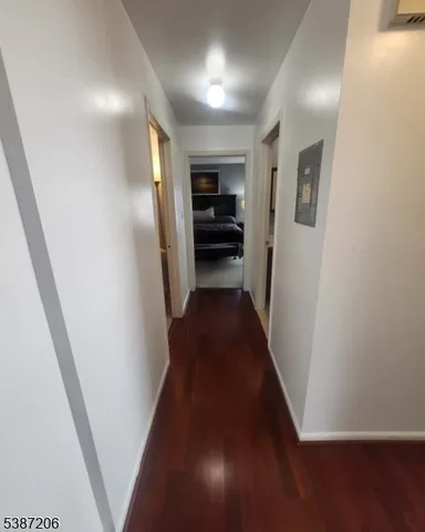 a view of a hallway to an empty room with wooden floor