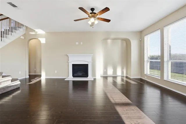 a view of an empty room with window and wooden floor