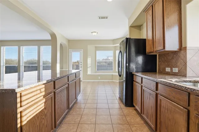a large kitchen with stainless steel appliances granite countertop a refrigerator and a sink