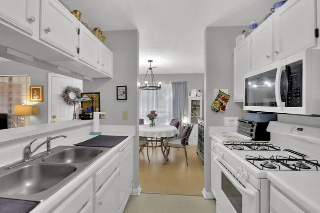 a kitchen with stainless steel appliances granite countertop a sink dishwasher a stove and a dining table with wooden floor