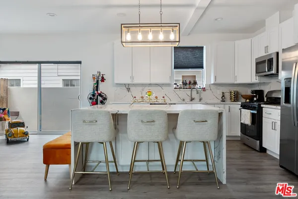 a kitchen with stainless steel appliances kitchen island granite countertop a sink a stove and a microwave