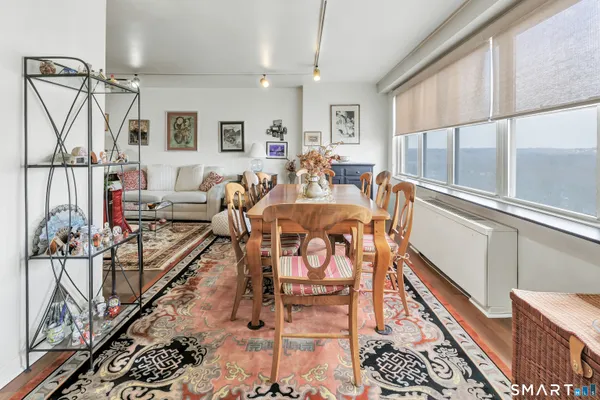 a very nice looking living room with a dining table a rug and wooden floor
