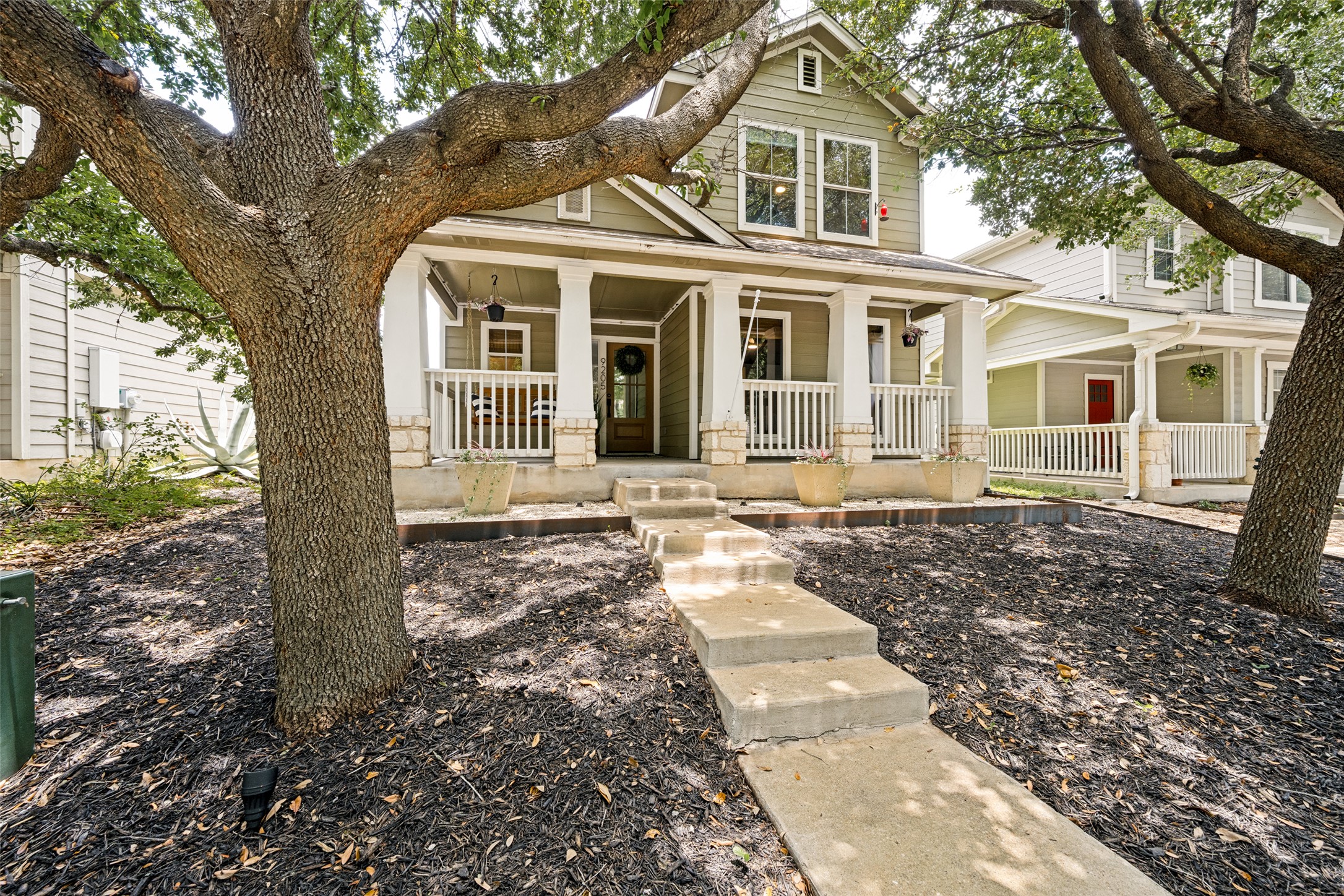 9205 Rowlands Sayle Road Austin, TX 78744 - Photo 2 of 25 A charming two-story residence with a welcoming front porch, shaded by mature trees.