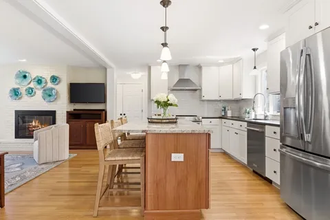 a kitchen with stainless steel appliances granite countertop a refrigerator a stove a sink dishwasher a oven with white cabinets and wooden floor