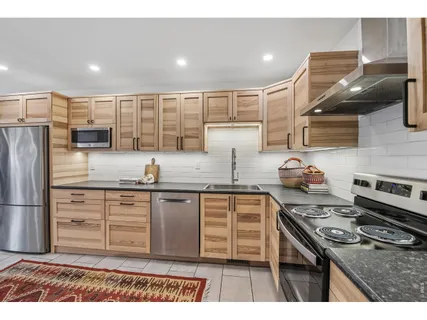 a kitchen with kitchen island granite countertop a sink cabinets and stainless steel appliances