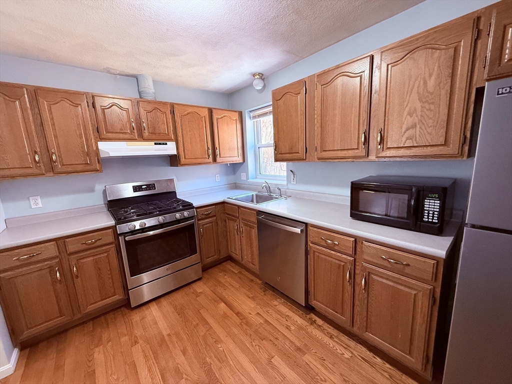 12 Regent Street, Unit 2F Cambridge, MA 02140 - Photo 8 of 29 a kitchen with granite countertop wooden cabinets and a stove top oven