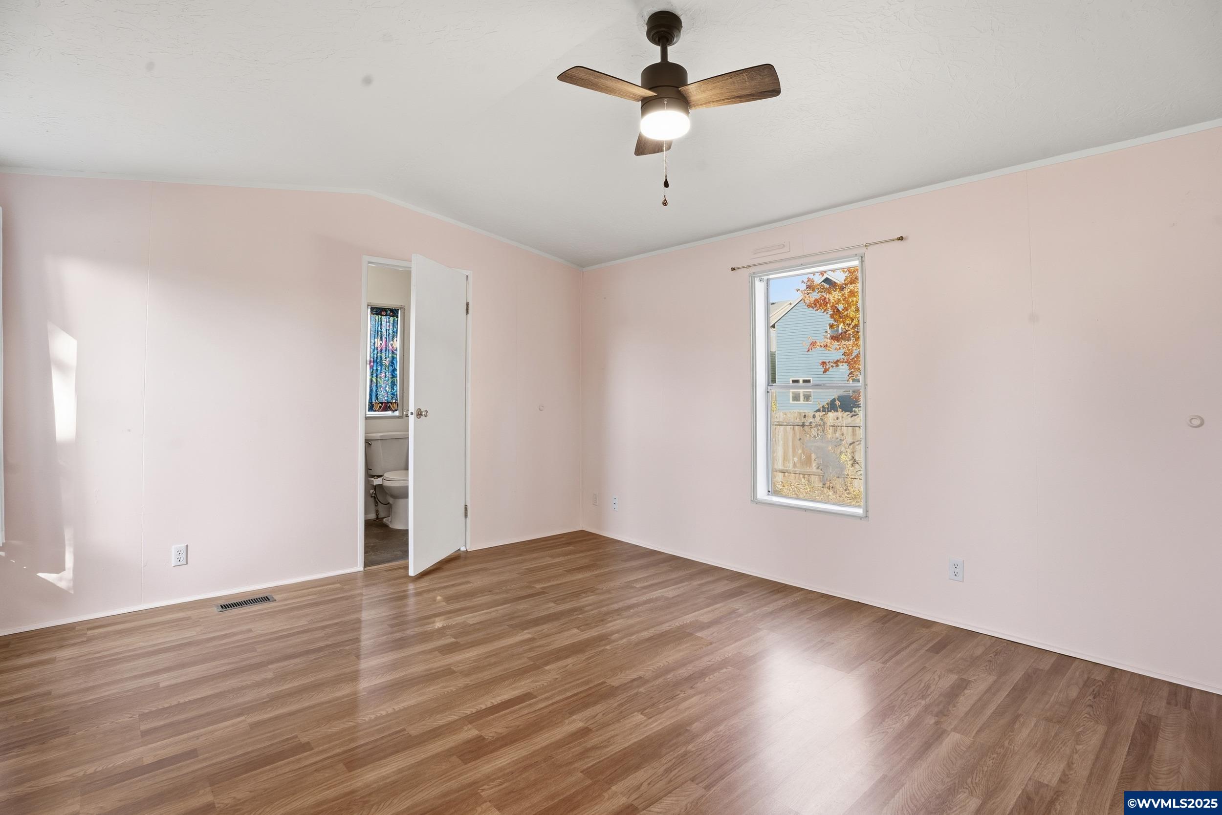 277 Edwards Road, Unit 145 Monmouth, OR 97361 - Photo 14 of 47 an empty room with wooden floor chandelier fan and windows