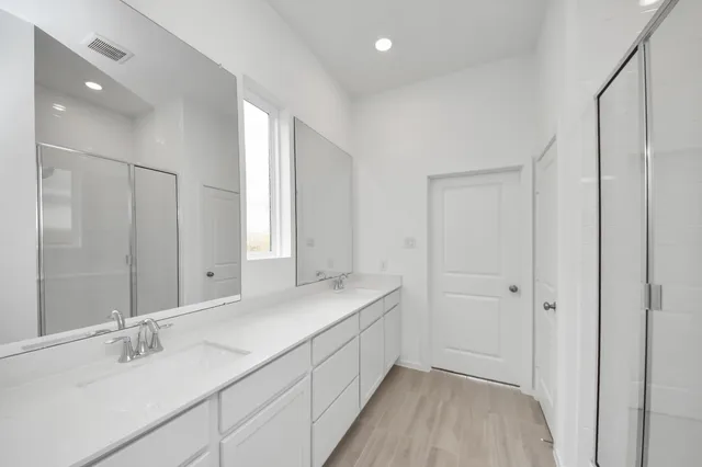 a bathroom with a double vanity sink and mirror with shower