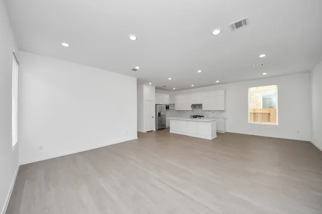a view of a kitchen with kitchen island a sink wooden floor and white cabinets
