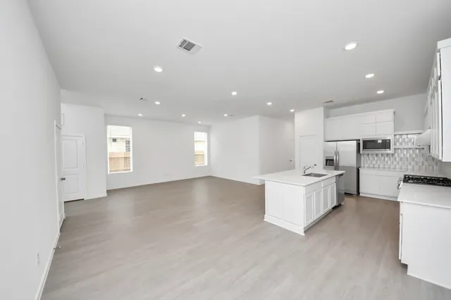 a view of kitchen with kitchen island sink refrigerator and white cabinets