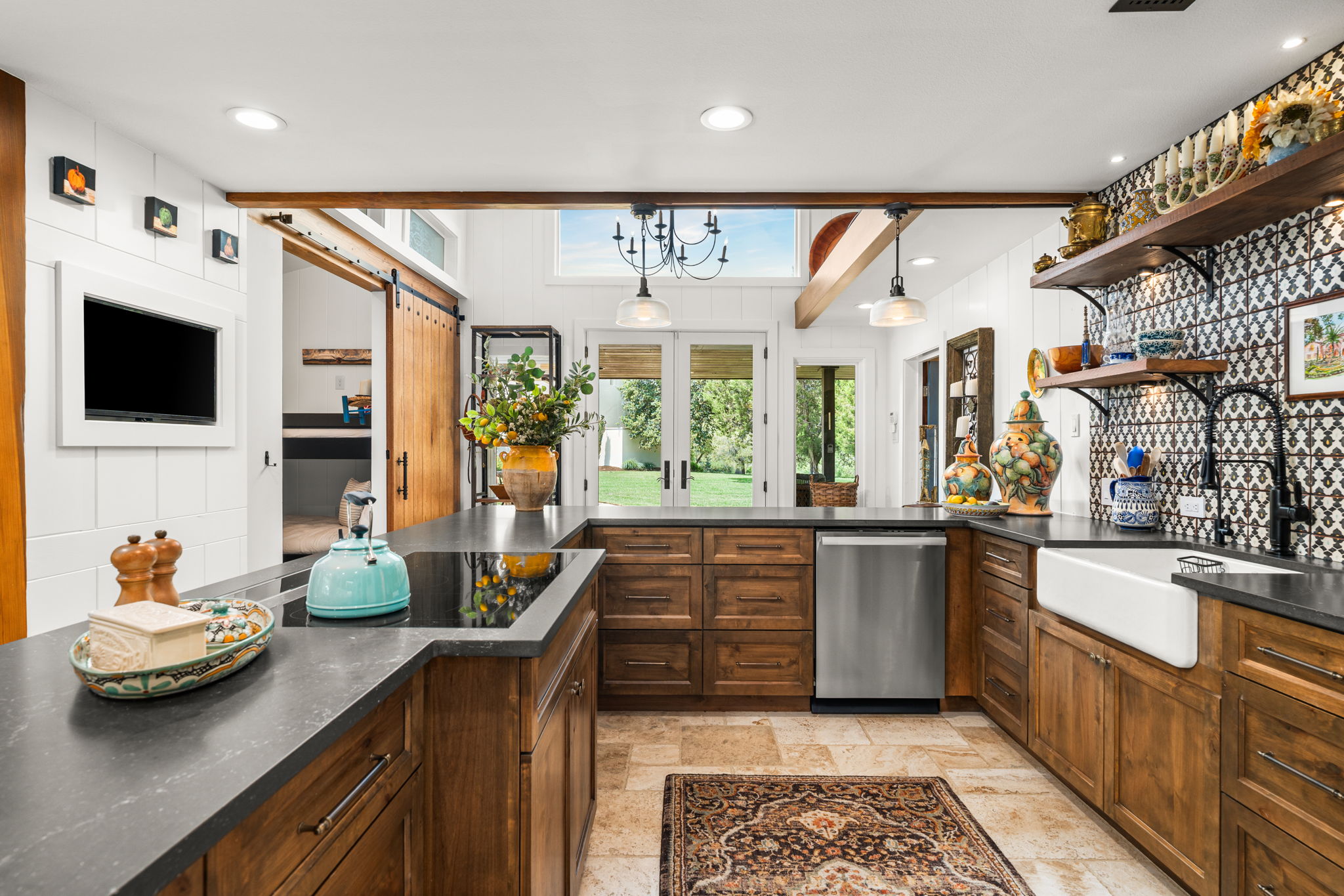 11941 Overlook Pass Austin, TX 78738 - Photo 13 of 40 Spacious kitchen featuring rich wood cabinetry, dark countertops, a large farmhouse sink, stainless steel appliances, and decorative tile backsplash