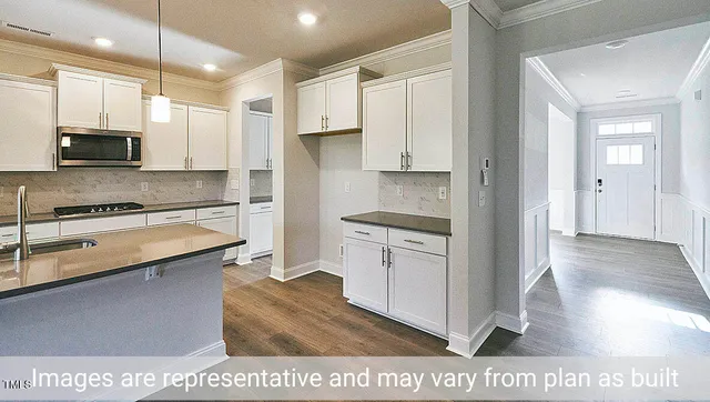 a kitchen with stainless steel appliances granite countertop a refrigerator a sink and white cabinets