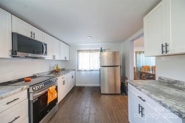 a kitchen with granite countertop stainless steel appliances a refrigerator stove top oven and sink