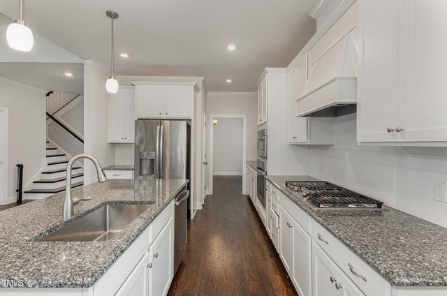 a open kitchen with granite countertop a stove a sink a center island and wooden floor