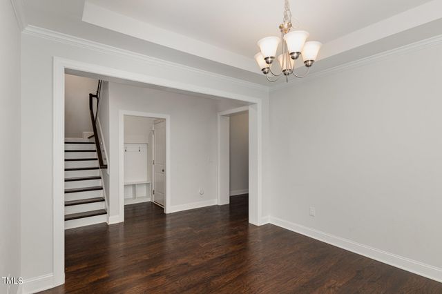 a view of an empty room with wooden floor and stairs