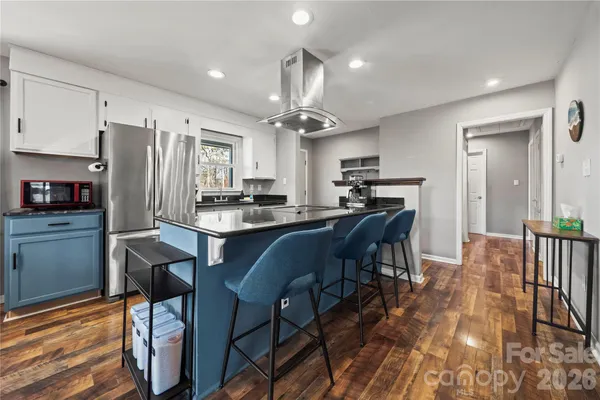 a kitchen with stainless steel appliances a dining table chairs stove refrigerator and cabinets