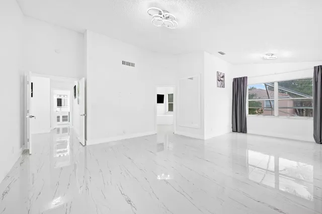 a view of a hallway with wooden floor and a bathroom