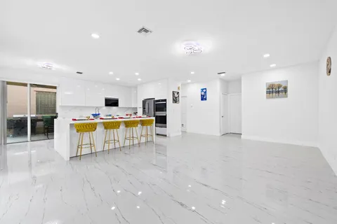 a living room with stainless steel appliances furniture and kitchen view