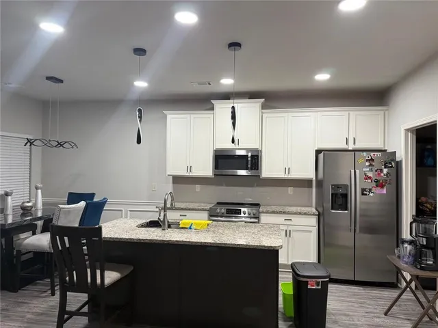 a kitchen with granite countertop white cabinets and stainless steel appliances