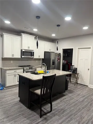 a living room with stainless steel appliances kitchen island granite countertop a table chairs and a stove