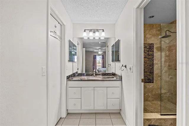 a bathroom with a granite countertop sink a mirror and shower