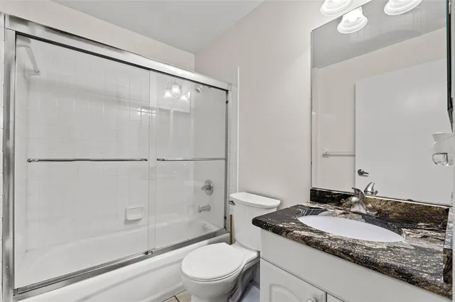 a bathroom with a granite countertop sink mirror toilet and bathtub