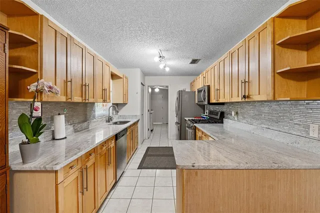 a kitchen with stainless steel appliances granite countertop a sink a stove and a wooden floors