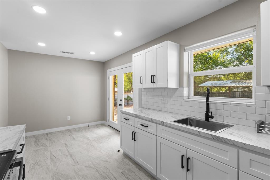 1903 Beauford Road Dallas, TX 75253 - Photo 10 of 27 Contemporary kitchen featuring white cabinetry, stone-finish countertops, stainless steel sink with matte black faucet, subway tile backsplash, and recessed lighting