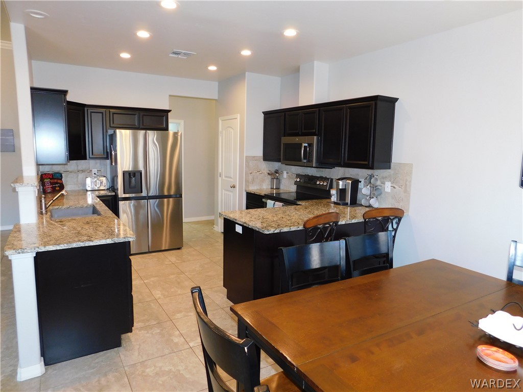 3370 South Ridge Avenue Bullhead City, AZ 86429 - Photo 29 of 56 a kitchen with stainless steel appliances kitchen island granite countertop a refrigerator and a stove top oven
