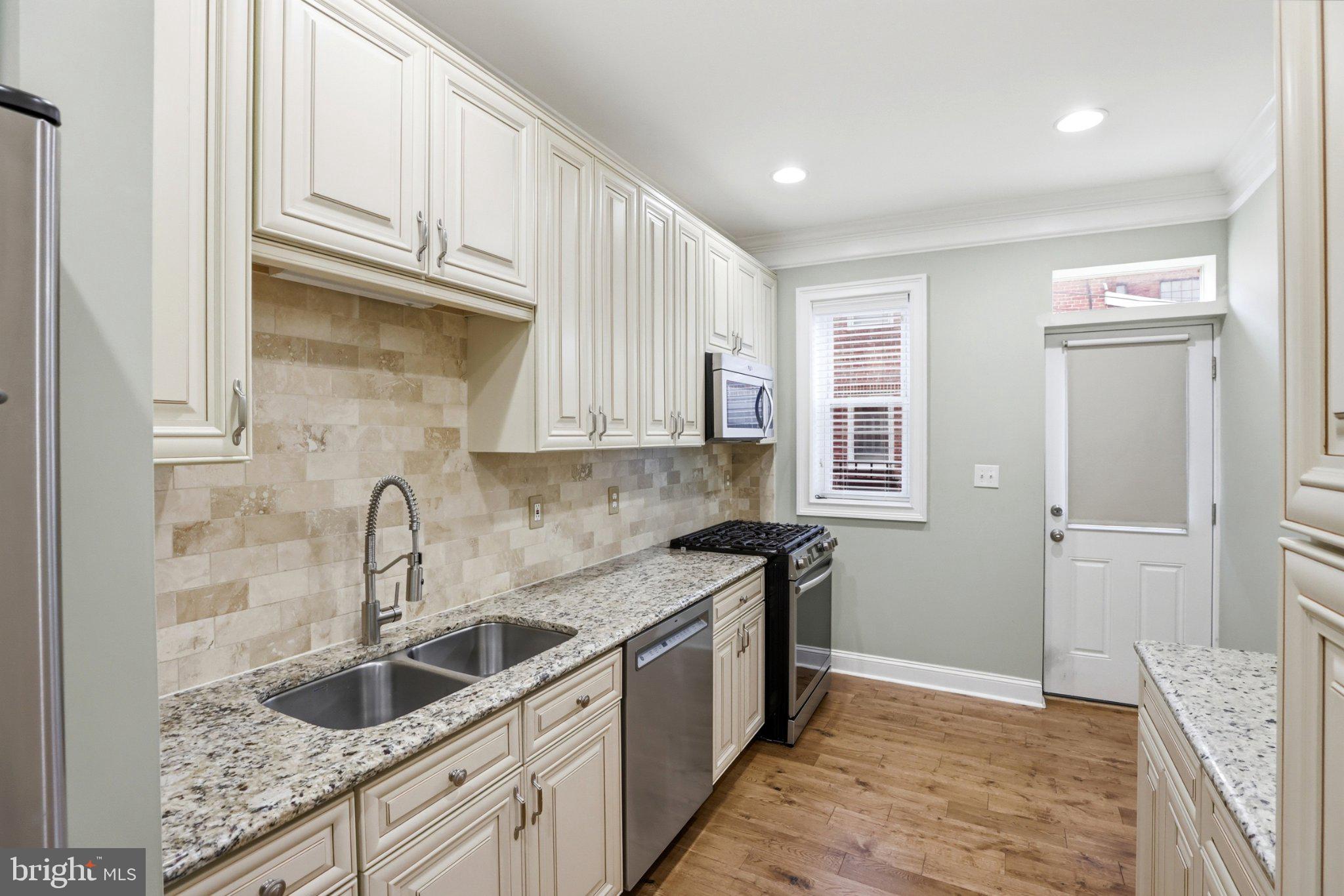 222 South Exeter Street Baltimore, MD 21202 - Photo 8 of 41 a kitchen with granite countertop a sink stove and cabinets