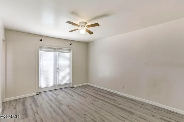 an empty room with wooden floor fan and windows