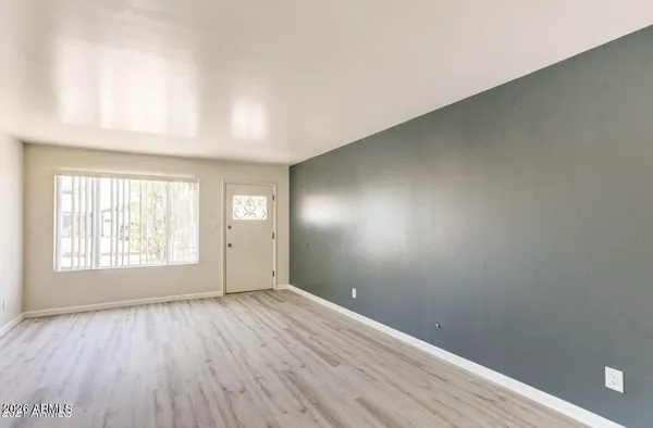 an empty room with wooden floor and windows