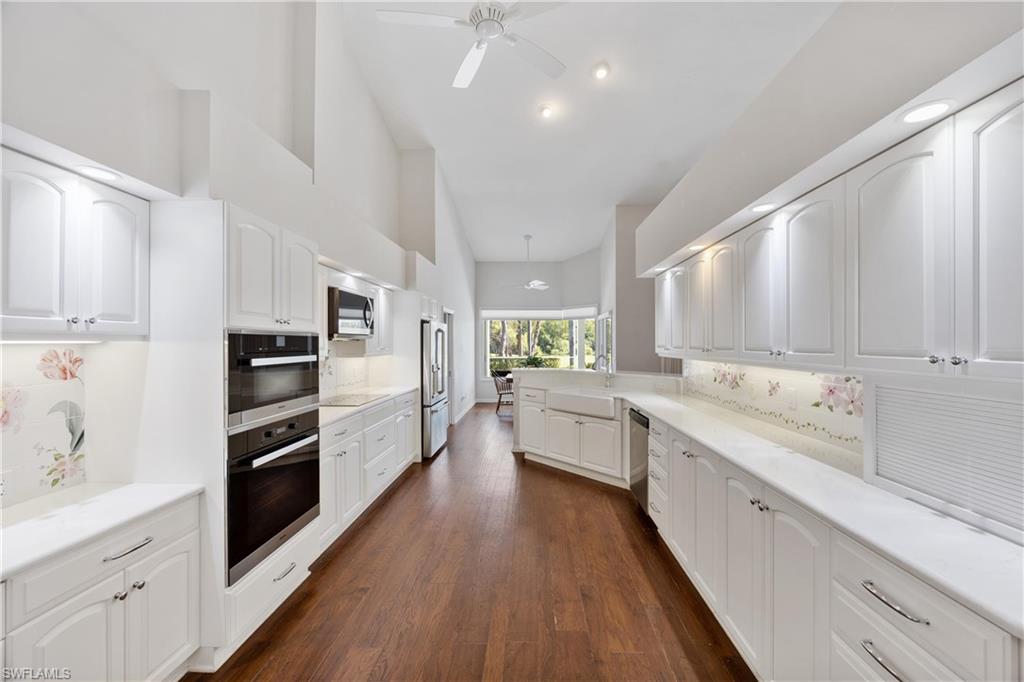 8992 Lely Island Circle Naples, FL 34113 - Photo 17 of 42 a large white kitchen with stainless steel appliances