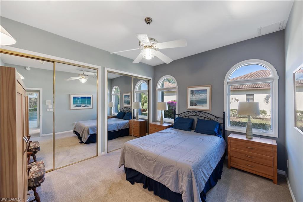 8992 Lely Island Circle Naples, FL 34113 - Photo 24 of 42 a bedroom with a large bed and a chandelier fan