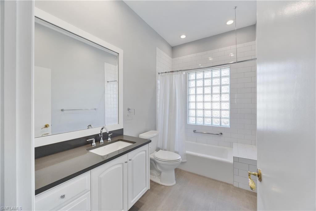 8992 Lely Island Circle Naples, FL 34113 - Photo 25 of 42 a bathroom with a double vanity sink toilet mirror and bathtub