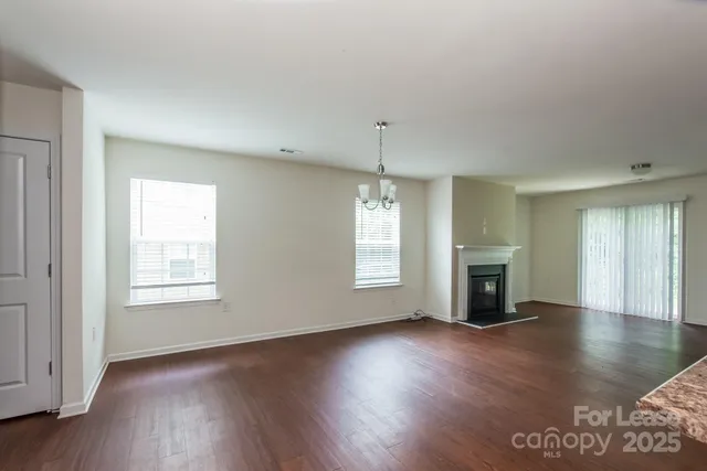 an empty room with wooden floor fireplace and windows