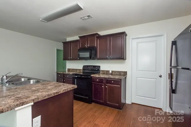 a kitchen with stainless steel appliances granite countertop a stove refrigerator and a sink