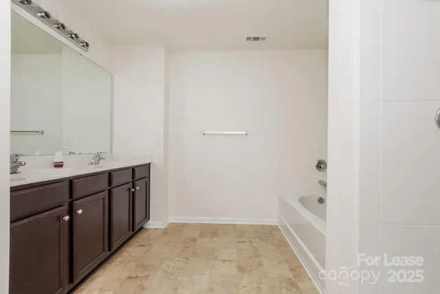 a bathroom with a tub sink and mirror