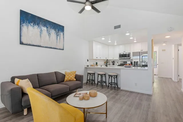 a living room with stainless steel appliances furniture and a dining table with wooden floor