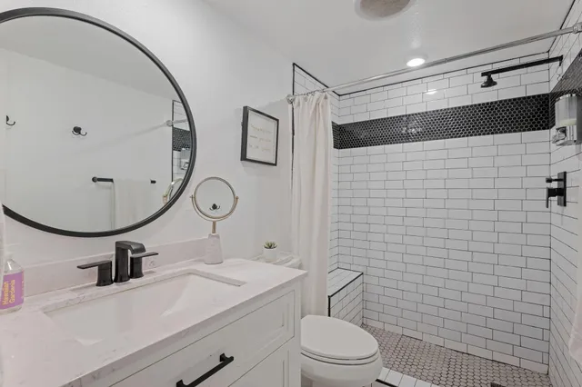 a bathroom with a toilet a sink a mirror and shower