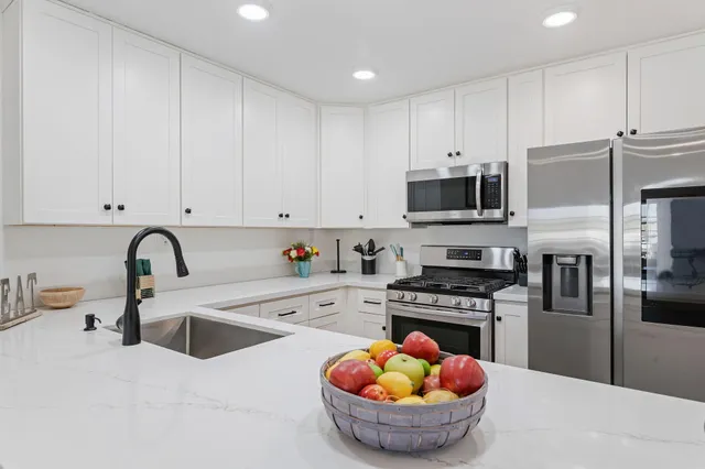 a kitchen with stainless steel appliances granite countertop a sink a stove and a refrigerator