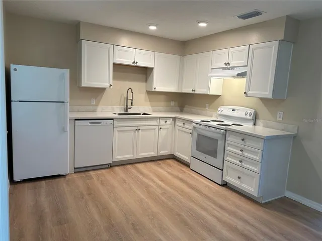 a kitchen with white cabinets stainless steel appliances and a refrigerator