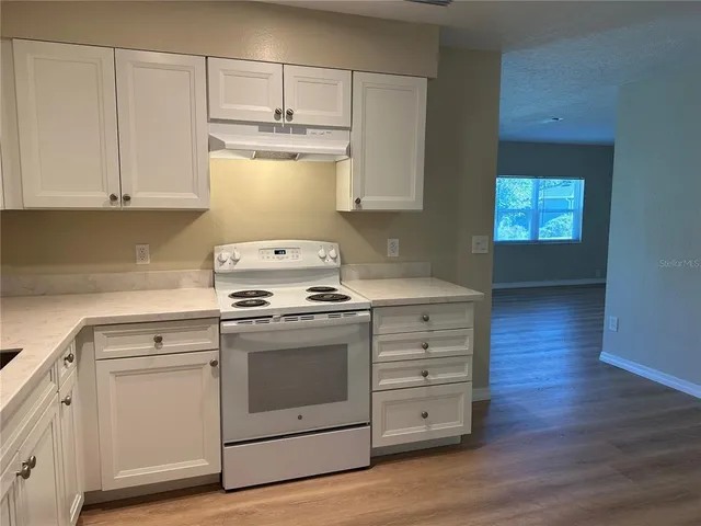 a kitchen with cabinets appliances and wooden floor