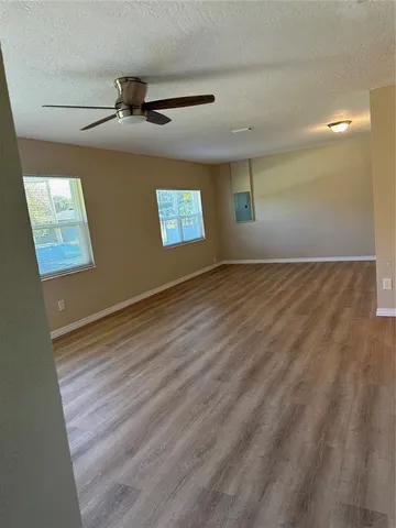 an empty room with wooden floor and windows