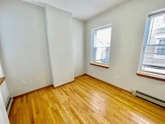 a view of an empty room with wooden floor and a bathroom