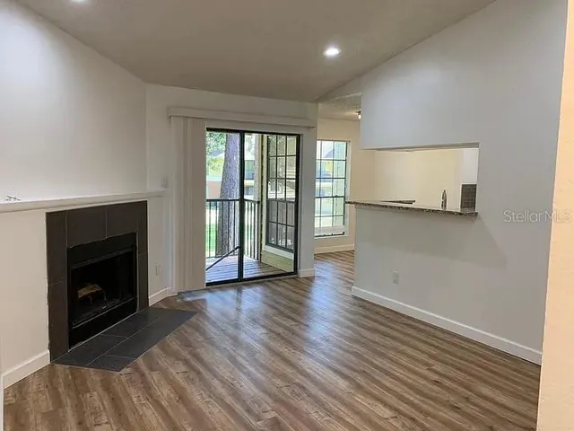 an empty room with wooden floor fireplace and windows